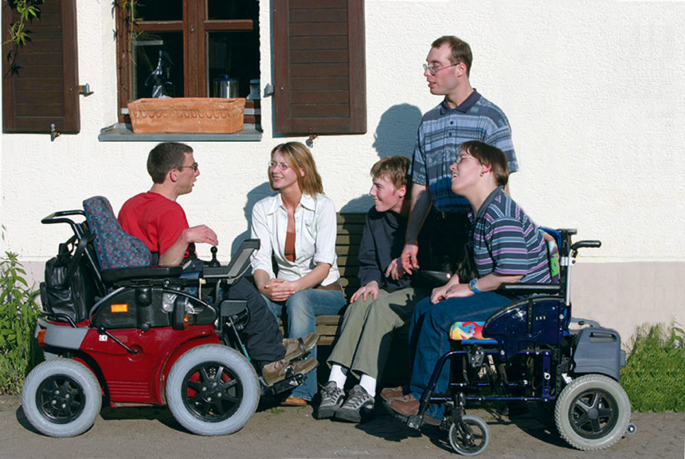Gruppe behindertet und nichtbehinderter Menschen vor dem Haus in der Sonne